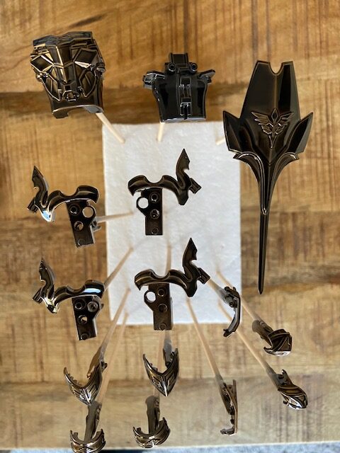 Image of a display of gundam parts that are black and gold.