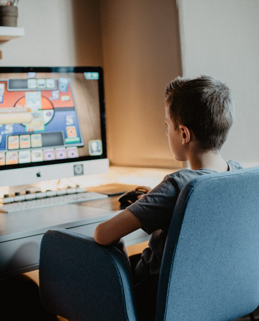 Image of a boy sitting in front of a computer screen playing an online game.