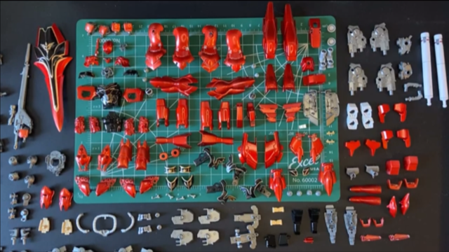 Image of disassembled gundam parts organized on a green hobby mat